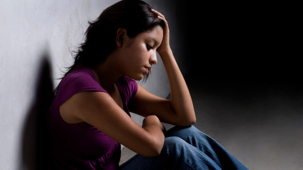 Woman sitting on the floor with her hand supporting her head.